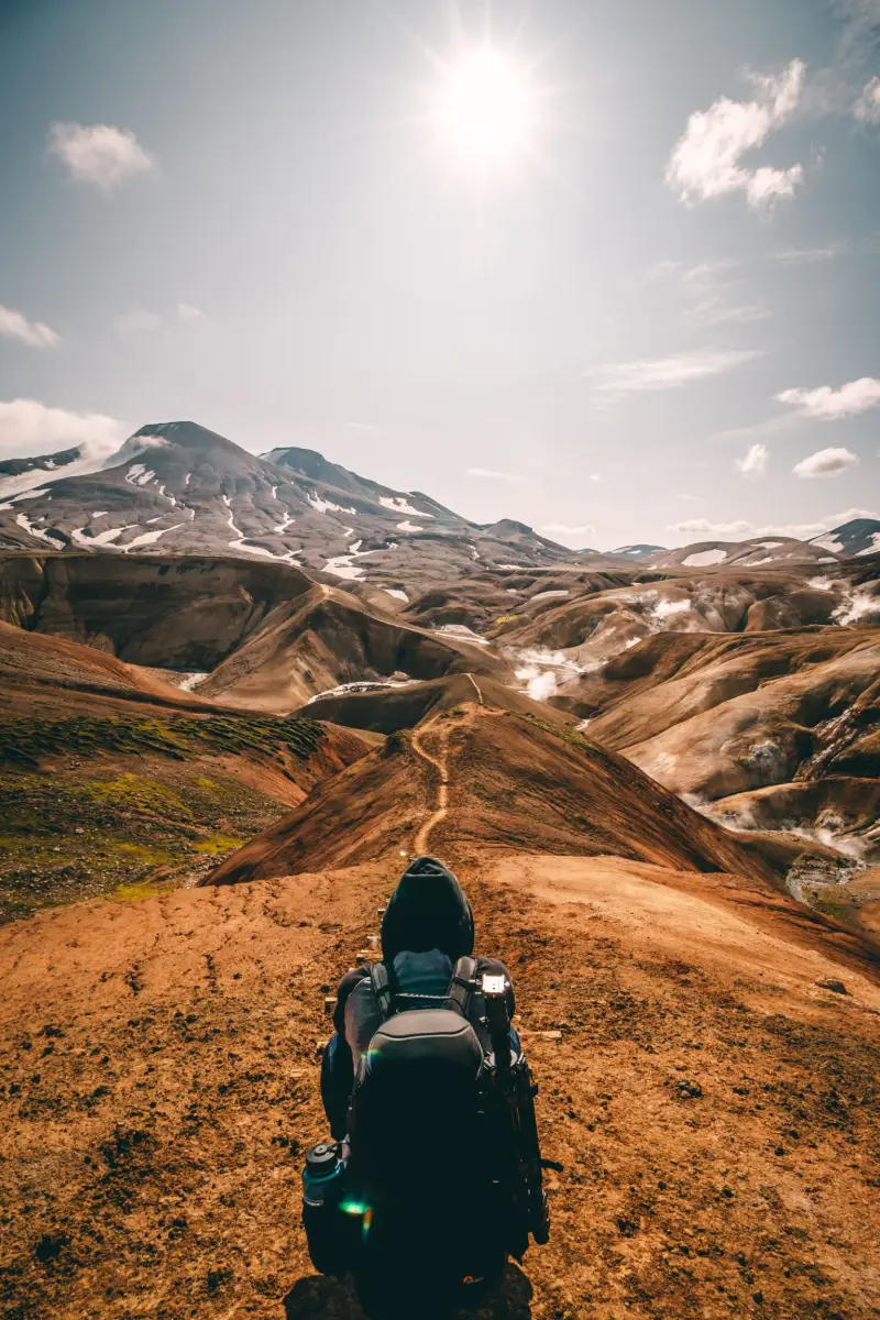 A hiker looking out over a winding trail toward distant peaks